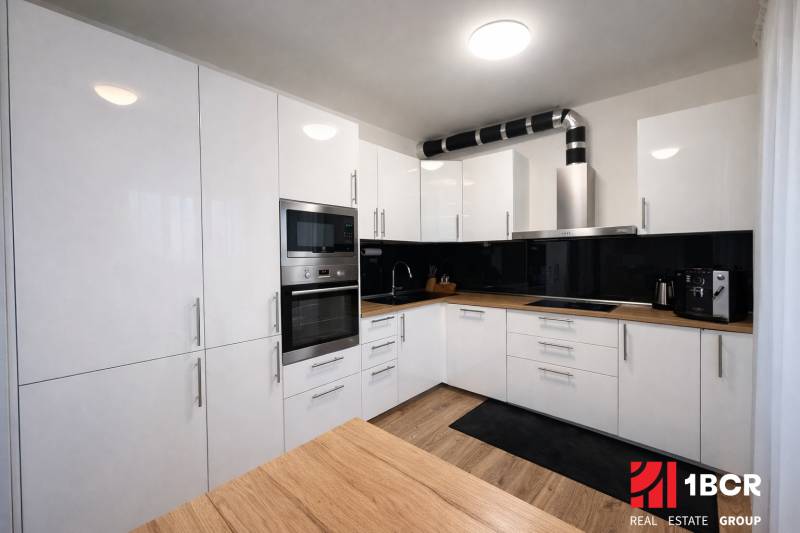 EXKLUZÍVNY 3-IZBOVÝ BYT V SÚKROMNOM KOMPLEXE |2x PARKING | NA PIESKU,  - Kuchyňa v 3-izbovom byte s bielymi skrinkami a podlahou s dreveným dekorom.