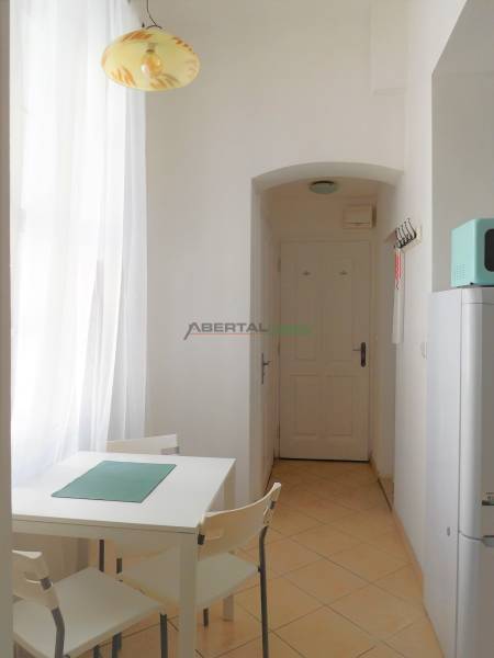 Predaj - štýlový 1,5i byt  v srdci Starého Mesta - Marianska, BA - Jedálenský kút so stolom, stoličkami, bielou stenou a zaveseným svetlom v 2-izbovom byte.