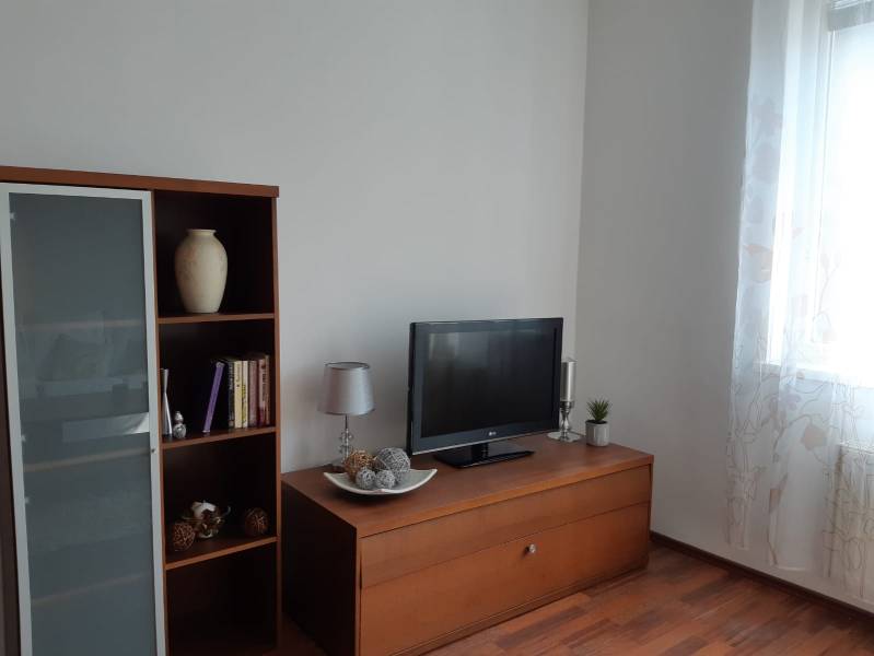 3 izb. byt v úplnom centre pri Šafárikovom námestí - Obývačka s podlahou s dreveným dekorom, knižnicou, televízorom a dekoratívnymi predmetmi.