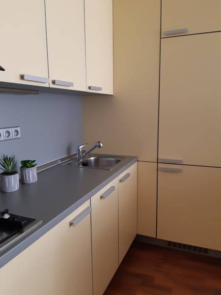 3 izb. byt v úplnom centre pri Šafárikovom námestí - Kuchyňa v 3-izbovom byte s krémovými skrinkami a podlahou s dreveným dekorom.