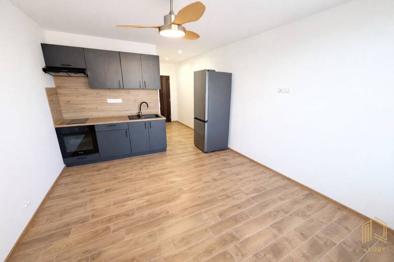 NA PRENÁJOM GARSÓNKA S BALKÓNOM, SENICA, ŠTEFÁNIKOVA UL. - Garsónka s kuchynskou linkou a podlahou s dreveným dekorom, chladnička.