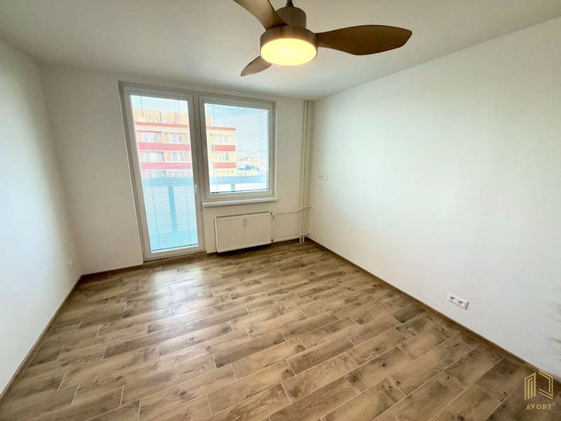 NA PRENÁJOM GARSÓNKA S BALKÓNOM, SENICA, ŠTEFÁNIKOVA UL. - Izba v garsónke s podlahou s dreveným dekorom, stropným ventilátorom a oknom s výhľadom.