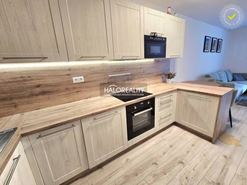 Predaj, dvojizbový byt Bratislava Podunajské Biskupi... - Kuchyňa s podlahou s dreveným dekorom v 2-izbovom byte, svetlé drevené skrinky a vstavané spotrebiče.