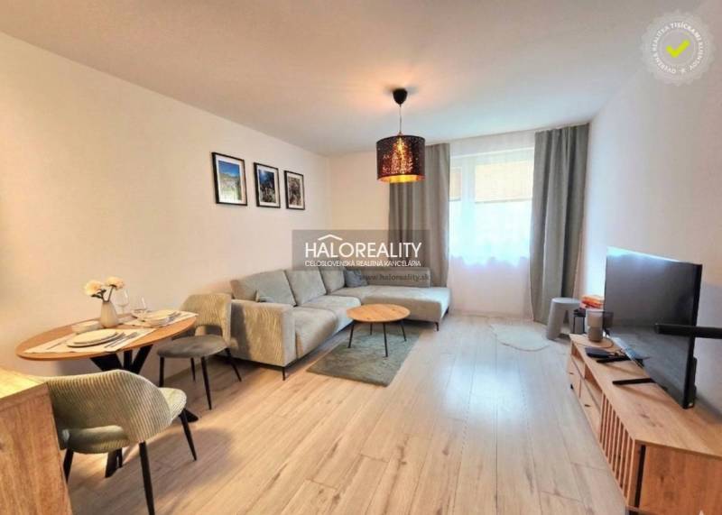 Predaj, dvojizbový byt Bratislava Podunajské Biskupi... - Obývacia izba v 2-izbovom byte s rohovou sedačkou a televízorom, podlaha s dreveným dekorom.