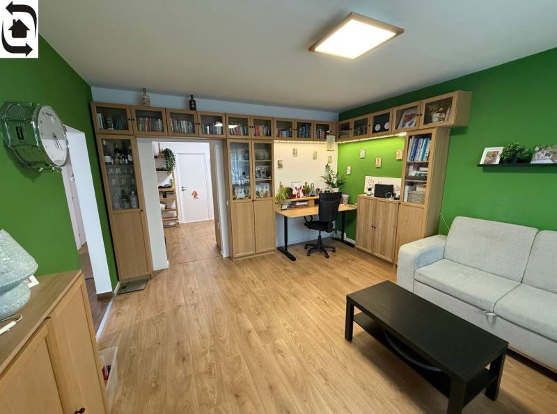 4 Izbový byt na Kríkovej ulici na predaj - Obývacia izba v 4-izbovom byte, s podlahou s dreveným dekorom a knihovňou.