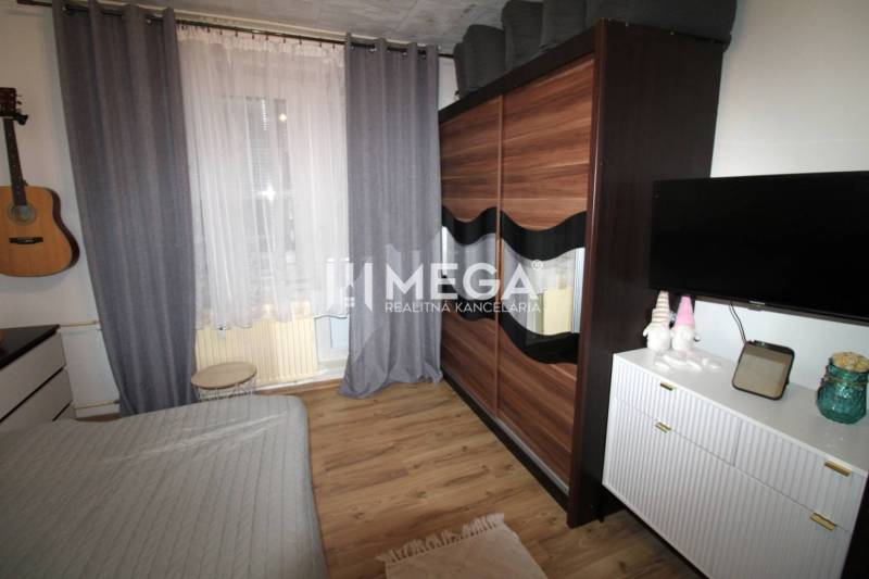 Na predaj 3 izbový byt na vynikajúcej adrese - Vranov nad Topľou - Izba v 3-izbovom byte s posteľou, skriňou a podlahou s dreveným dekorom.