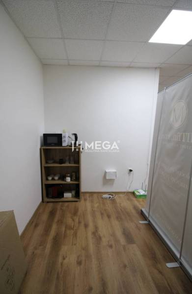 NA PRENÁJOM - obchodný priestor v OD Laborec, pešia zóna mesta Humenné - Interiér obchodných priestorov s policou, mikrovlnkou a podlahou s dreveným dekorom.