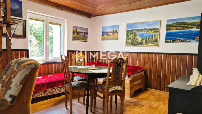 PREDAJ REKREAČNEJ CHATY NA DOMAŠI časť DOBRÁ - Izba na chate s dreveným stropom a podlahou s dreveným dekorom, obrazy na stenách.