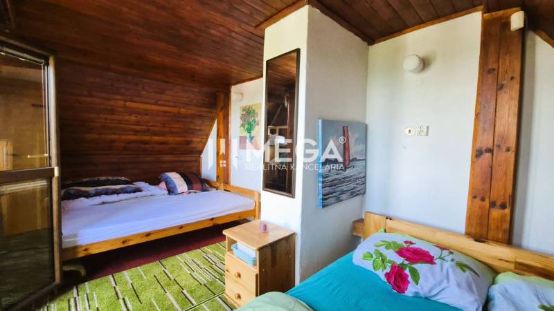 PREDAJ REKREAČNEJ CHATY NA DOMAŠI časť DOBRÁ - Interiér chaty s dreveným obkladom, dvoma posteľami a nočným stolíkom.