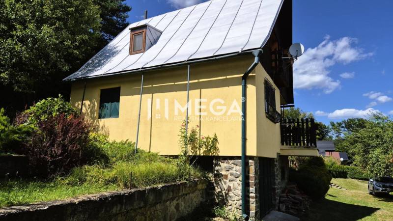 PREDAJ REKREAČNEJ CHATY NA DOMAŠI časť DOBRÁ - Chata na Vodárenskej ulici v Kvakovciach obklopená zeleňou a prírodou, s modrou oblohou.