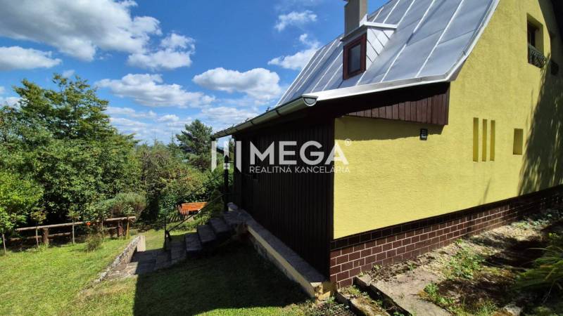 PREDAJ REKREAČNEJ CHATY NA DOMAŠI časť DOBRÁ - Chata na Vodárenskej ulici v Kvakovciach obklopená zeleňou, modrá obloha.