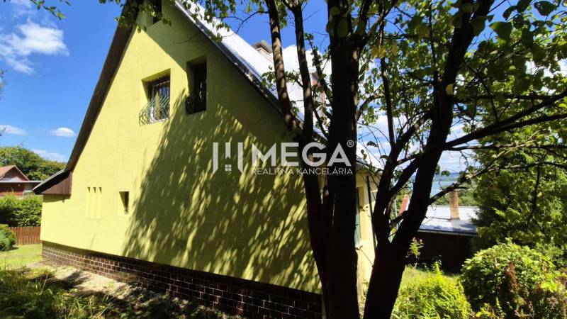 PREDAJ REKREAČNEJ CHATY NA DOMAŠI časť DOBRÁ - Chata na Vodárenskej ulici v Kvakovciach obklopená zeleňou a stromami.