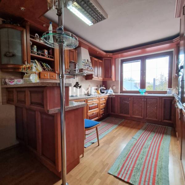 SKVELÁ CENA - výnimočný  rodinný dom, Kamenica nad Cirochou - Kuchyňa v rodinnom dome s podlahou s dreveným dekorom, drevenými skrinkami a oknom.