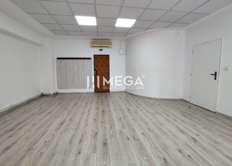 NA PRENÁJOM - kancelárske priestory v cente mesta Michalovce - Prázdna kancelária s bielymi stenami a podlahou s dreveným dekorom.