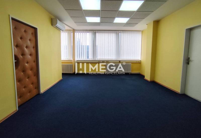 NA PRENÁJOM - kancelárske priestory v cente mesta Michalovce - Žlté steny v kancelárii s tmavým kobercom a oknami so žalúziami.