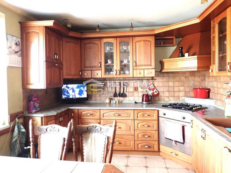 ZNÍŽENÁ CENA Veľký 2-izbový investičný byt Senica - 73,54 m² - Kuchyňa s drevenými skrinkami v 2-izbovom byte, keramický obklad, televízor, kuchynský riad.