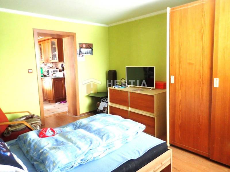 ZNÍŽENÁ CENA Veľký 2-izbový investičný byt Senica - 73,54 m² - Izba v 2-izbovom byte s televízorom, šatníkom a podlahou s dreveným dekorom.