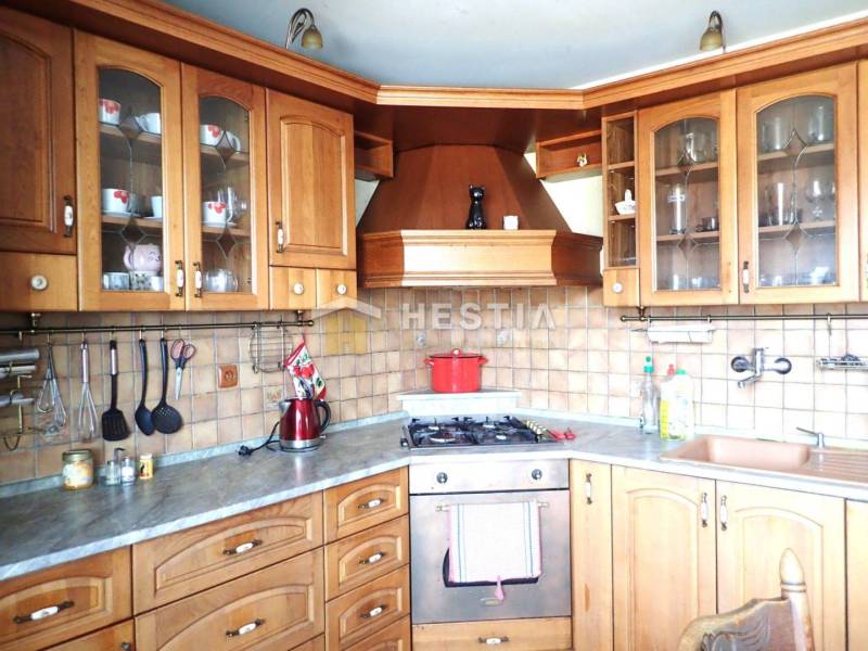 ZNÍŽENÁ CENA Veľký 2-izbový investičný byt Senica - 73,54 m² - Kuchyňa v 2-izbovom byte so skrinkami a spotrebičmi na pozadí dlaždicovej steny.