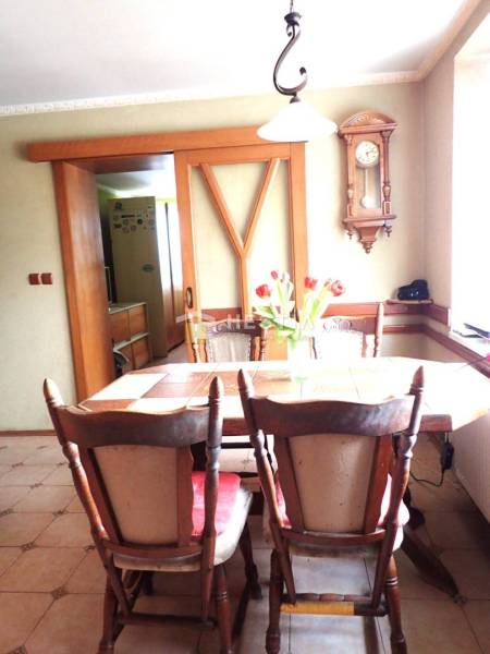 ZNÍŽENÁ CENA Veľký 2-izbový investičný byt Senica - 73,54 m² - Jedáleň v 2-izbovom byte s dreveným stolom, retro hodiny na stene.