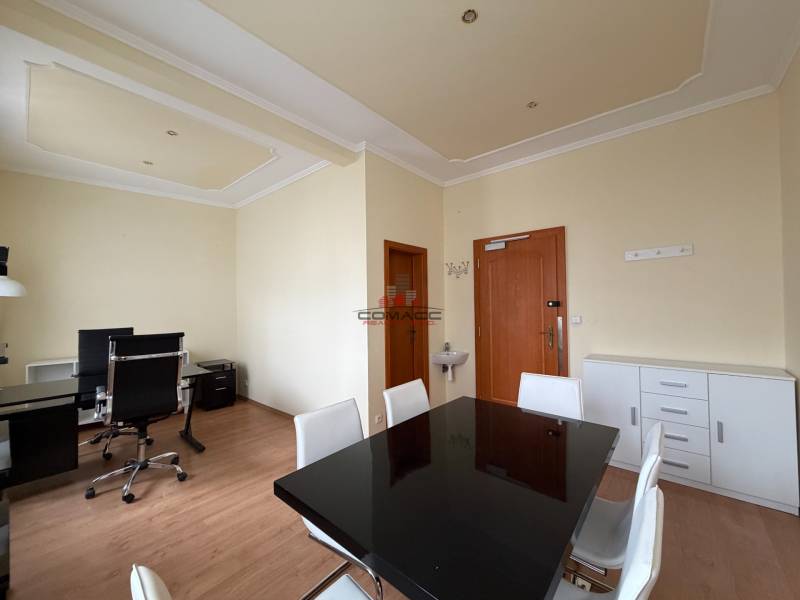 Prenájom kancelárie 33 m2 v centre Piešťan - Kancelárie s podlahou s dreveným dekorom, čiernym stolom a ergonomickými stoličkami.