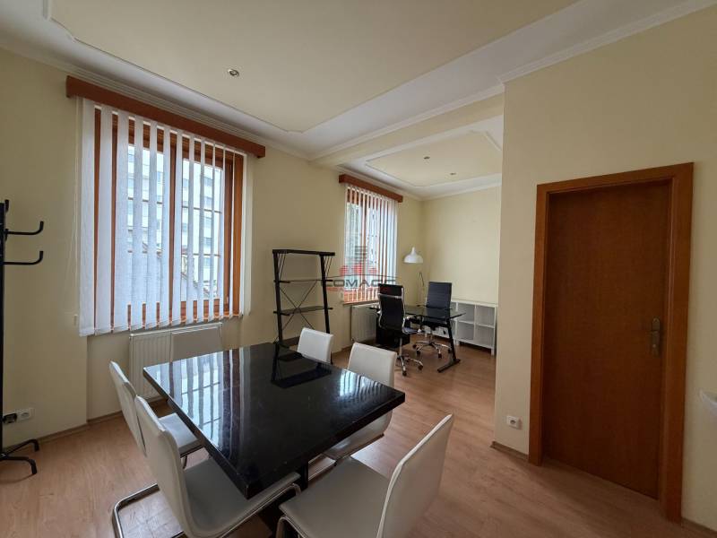 Prenájom kancelárie 33 m2 v centre Piešťan - Kancelárie s podlahou s dreveným dekorom, čiernym stolom a bielymi stoličkami.