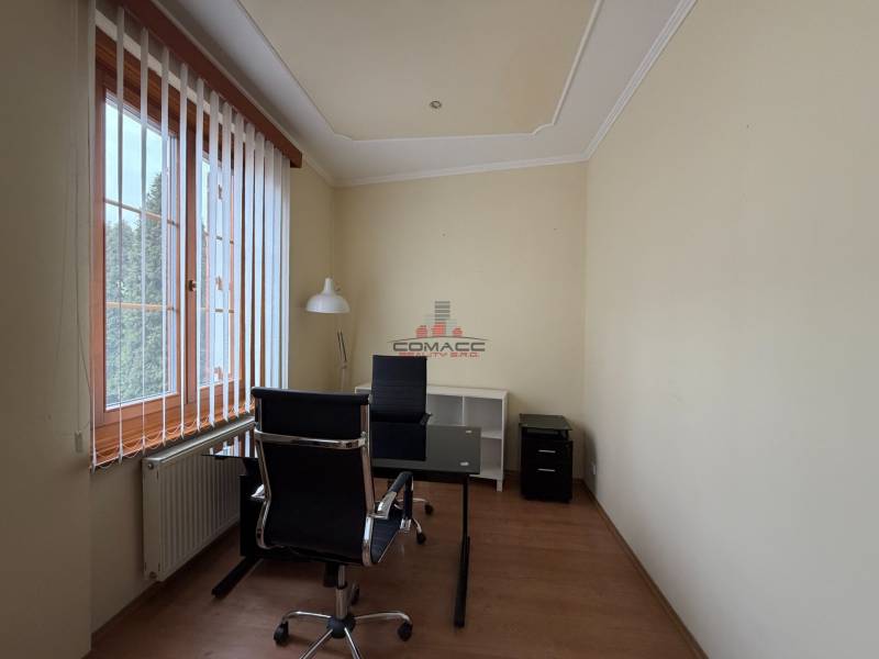 Prenájom kancelárie 33 m2 v centre Piešťan - Kancelárie s jedným stolom, stoličkou a svietidlom s dreveným dekorom podlahy.