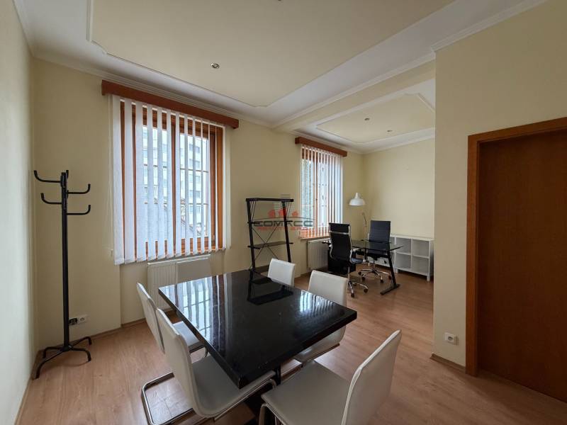 Prenájom kancelárie 33 m2 v centre Piešťan - Interiér kancelárie s podlahou s dreveným dekorom, vybavený stolmi a stoličkami.