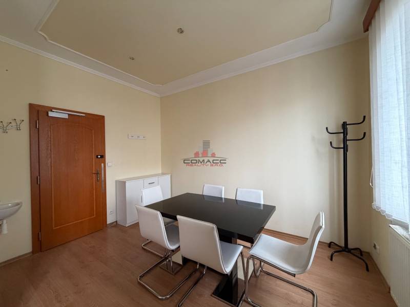 Prenájom kancelárie 33 m2 v centre Piešťan - Kancelárie s podlahou s dreveným dekorom, čiernym stolom a bielymi stoličkami.