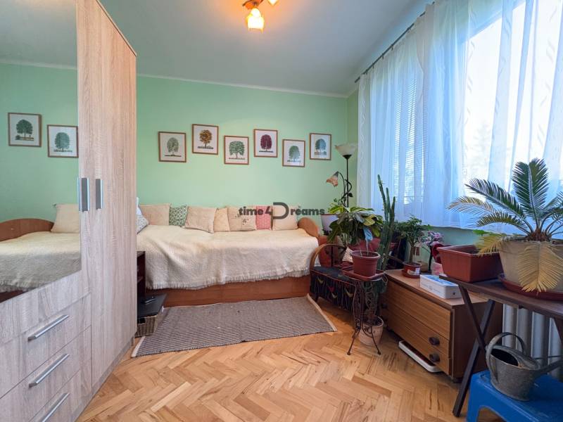 Na predaj: 4 izb.byt + BALKON + ŠATNIK + ŠPAJZA - Izba v 3-izbovom byte s dekoratívnymi rastlinami a podlahou s dreveným dekorom.