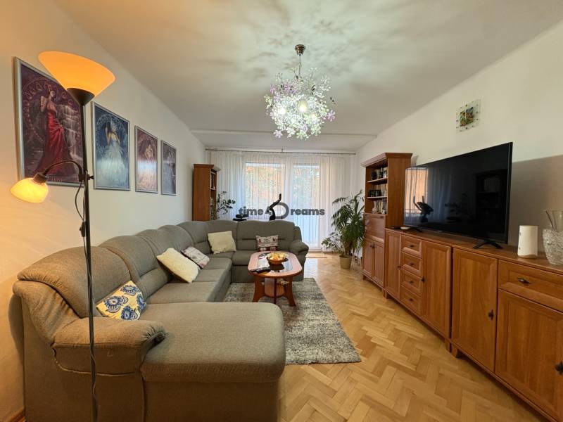 Na predaj: 4 izb.byt + BALKON + ŠATNIK + ŠPAJZA - Obývacia izba s pohovkou a podlahou s dreveným dekorom v 3-izbovom byte.