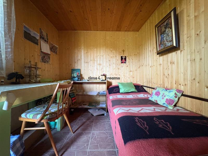 Na predaj: Ovocná záhrada v Leviciach - Drevený interiér s posteľou, stolom a stoličkou v Záhradách.