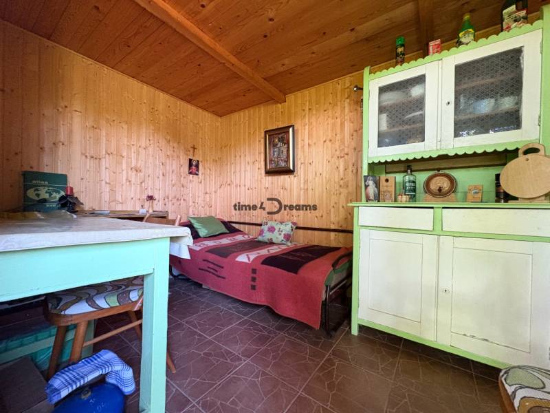 Na predaj: Ovocná záhrada v Leviciach - Interiér izby so zeleným nábytkom a drevenými stenami v Záhradách.