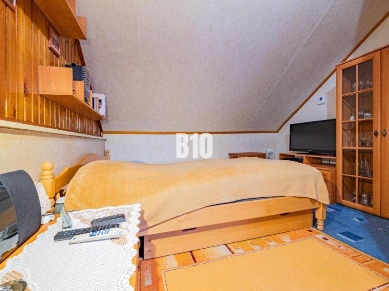 POD HRADOM bývanie alebo podnikanie - Podkrovná spálňa s dreveným nábytkom v rodinnom dome.