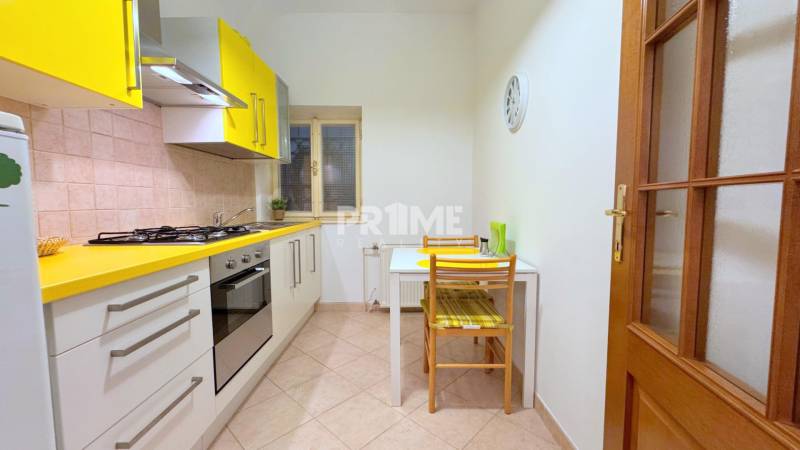 EXKLUZÍVNE, Štýlový 2i byt,, Hviezdoslavovo námestie, Staré.Mesto  - Kuchyňa v 2-izbovom byte s pestrými žltými skrinkami, stôl a stoličky priestor dopĺňajú.