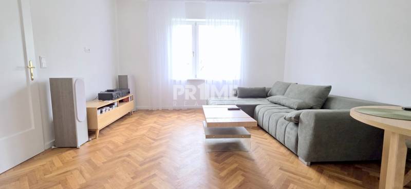 Pekný 3i byt, REKONŠTRUKCIA, KLÍMA, NIVY, Trenčianska ulica - Svetlá obývačka v 3-izbovom byte s pohodlnou sedačkou, stolíkom a výhľadom na ulici Trenčianska.