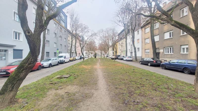 Pekný 3i byt, REKONŠTRUKCIA, KLÍMA, NIVY, Trenčianska ulica - Ulica Trenčianska s 3-izbovým bytom, autá parkované popri chodníku, stromy, sídlisko.