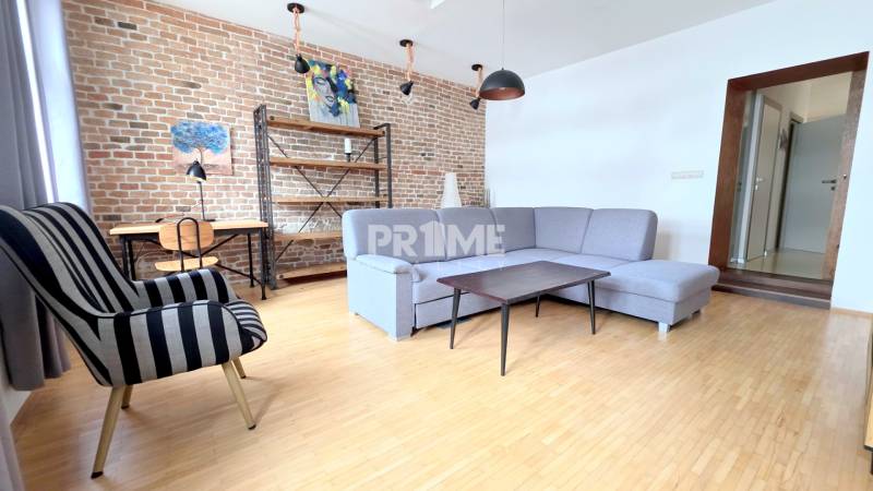 JEDINEČNÝ 2i byt, REKONŠT., 2 X .SAMOST.IZBA, Hviezdoslavovo nám.  - Obývacia izba v 2-izbovom byte s tehlovou stenou a podlahou s dreveným dekorom.