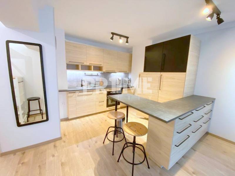 ŠTÝLOVÝ 2i byt, NOVOSTAVBA, BALKÓN, PARKIN, Paričková ulica, NIVY - Kuchyňa v 2-izbovom byte na Páričkovej s drevenými skriňami a barovým pultom.