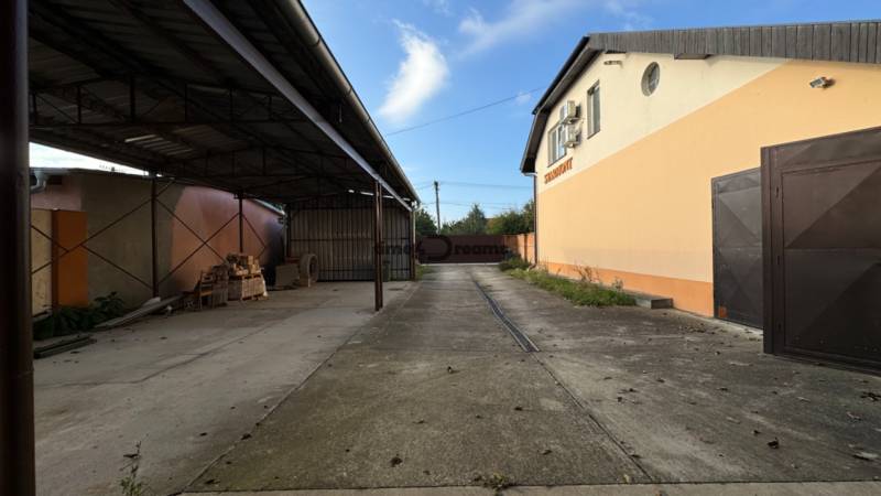 NA PREDAJ rodinný dom/polyfunkcia Komjatice  - Priemyselný areál s prístreškom a asfaltovou cestou, blízko rodinnému domu.