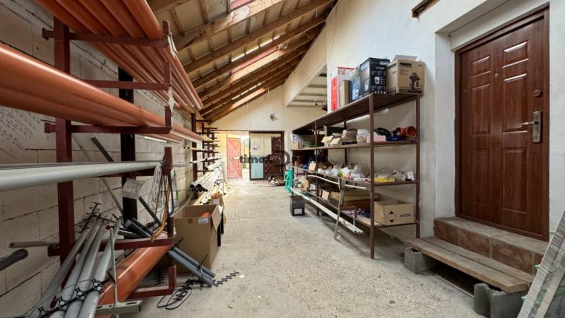 NA PREDAJ rodinný dom/polyfunkcia Komjatice  - Skladový priestor v rodinnom dome s regálmi a stavebným materiálom.