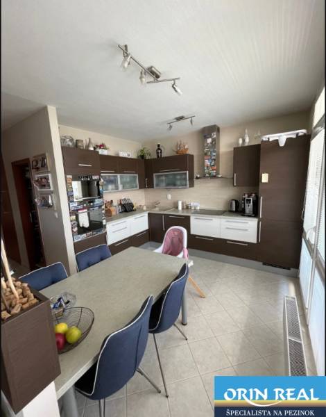 PREDAJ PRIESTRANNÉHO 3 IZB. BYTU NA MUŠKÁTE S GARÁŽOVÝM STÁTIM - Kuchyňa v 3-izbovom byte s tmavým nábytkom a jedálenským stolom.