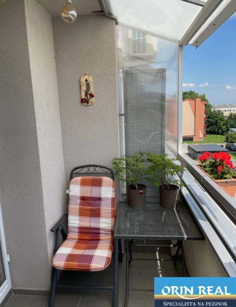 PREDAJ PRIESTRANNÉHO 3 IZB. BYTU NA MUŠKÁTE S GARÁŽOVÝM STÁTIM - Balkón 3-izbového bytu na Silvanovej ulici v Pezinku so sedením a rastlinami.