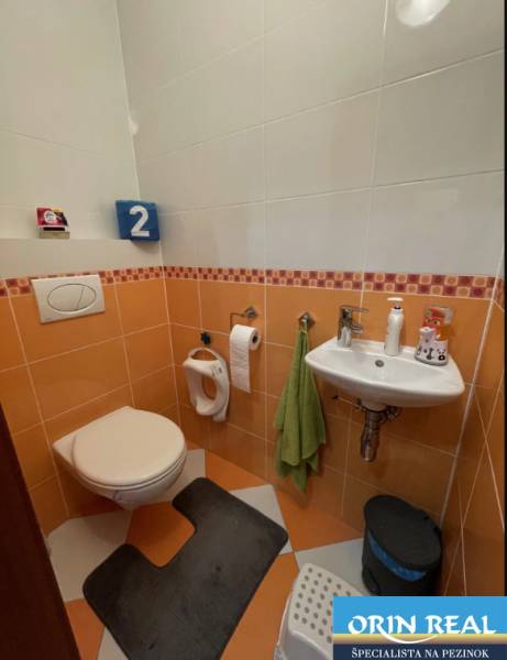 PREDAJ PRIESTRANNÉHO 3 IZB. BYTU NA MUŠKÁTE S GARÁŽOVÝM STÁTIM - Kúpeľňa v 3-izbovom byte s oranžovými obkladmi, vybavená toaletou a umývadlom.