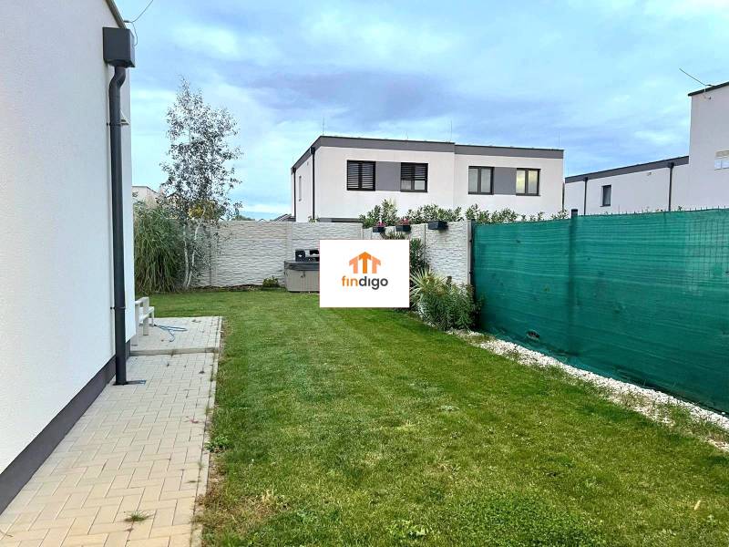 PRENÁJOM - 4 izbový rodinný dom, ktorý je súčasťou dvojdomu   - Dvor rodinného domu v Chorvátskom Grobe s trávnikom a dlažbou, obklopený plotom.