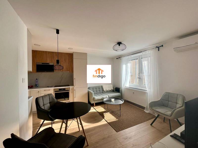 PRENÁJOM - 3-izbový krásny kompletne zrekonštruovaný byt - Mostná - Obývacia izba 3-izbového bytu so sedačkou, podlahou s dreveným dekorom a jedálenským stolom.