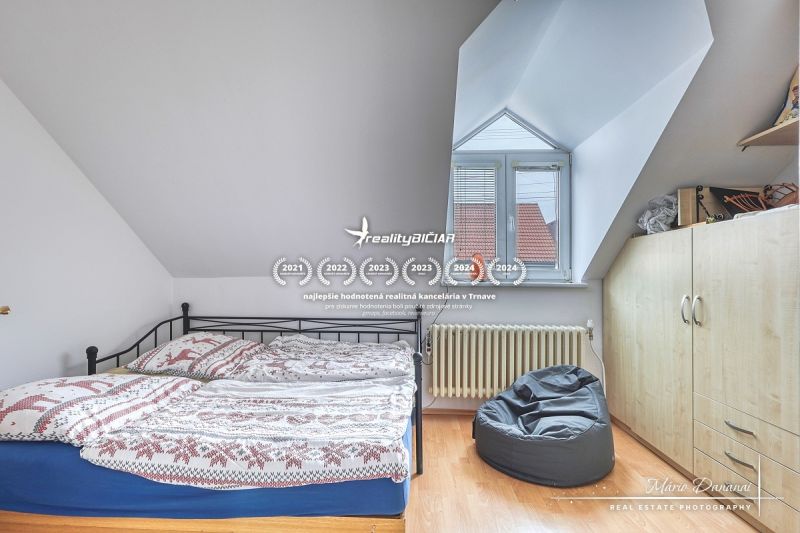 NOVÁ CENA - 5-izbový rodinný dom, dve garáže a krásny pozemok Špačince - Spálňa v rodinnom dome s posteľou, vreckovým kreslom a podlahou s dreveným dekorom.