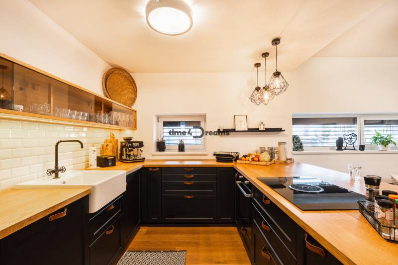 NA PREDAJ Krásny domček v Ivánke pri Nitre - Kuchyňa v rodinnom dome s podlahou s dreveným dekorom a keramickým drezom.