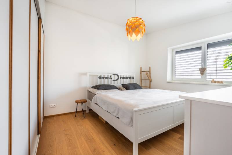 NA PREDAJ Krásny domček v Ivánke pri Nitre - Spálňa v rodinnom dome s bielym nábytkom a podlahou s dreveným dekorom.