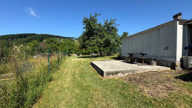 NA PREDAJ krásny pozemok pre váš nový Dom alebo Chalupu - Oplotený pozemok v Nová Baňa s trávou a stromami, ideálny na bývanie.