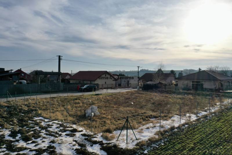 NA PREDAJ Stavebný pozemok v obci Golianovo - Pozemky - bývanie v Golianove, dedinské domy, cesta a zasnežená krajina pod oblohou.